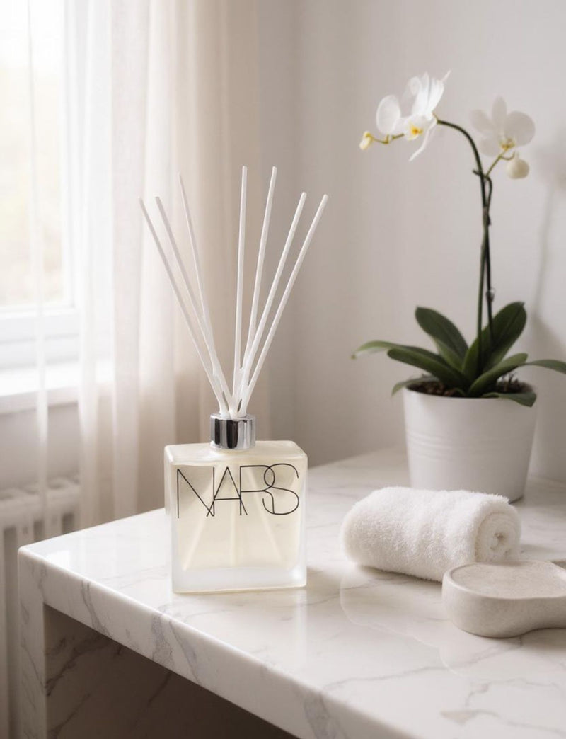 NARS diffuser bottle on a marble surface with an orchid and towel in the background