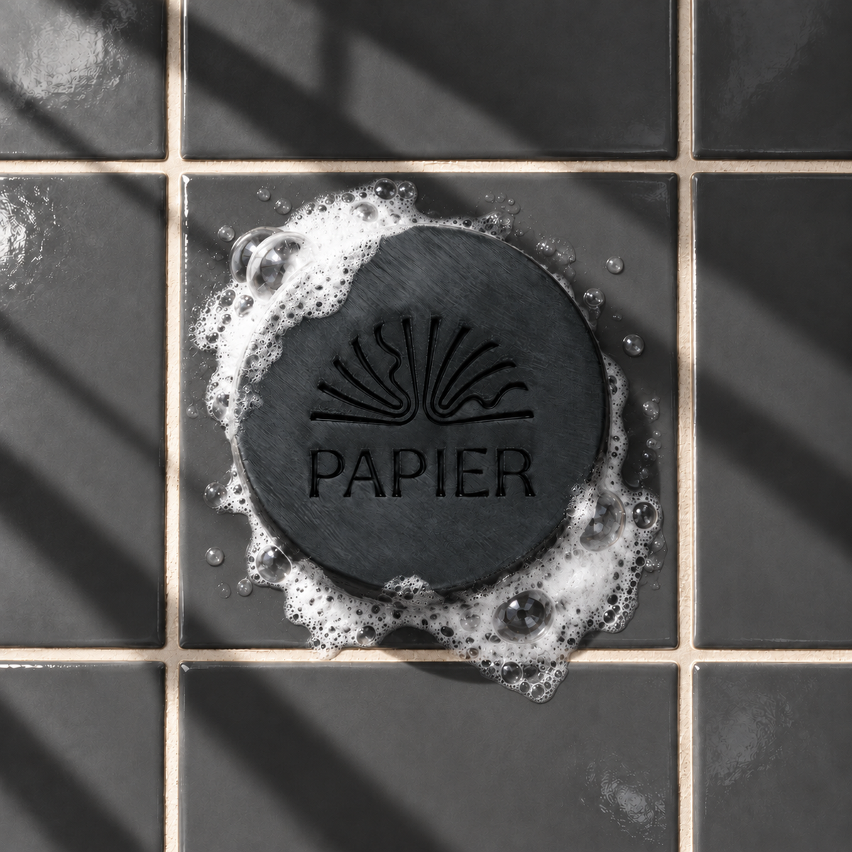 Black round bar soap laser engraved with a brand logo, 3.6 oz, with soap bubbles