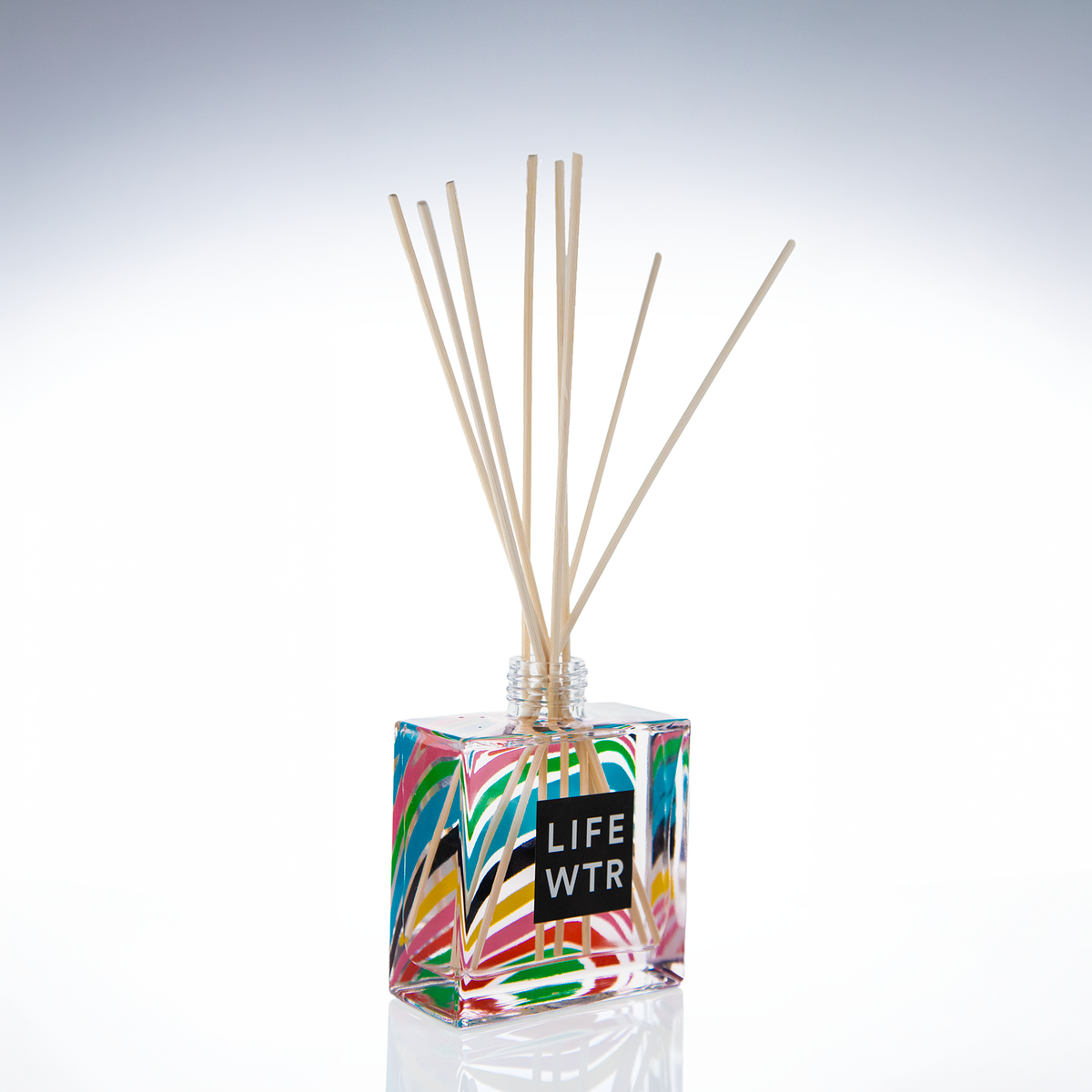 Clear glass 8 oz reed diffuser with a colorful wrap print and natural reeds