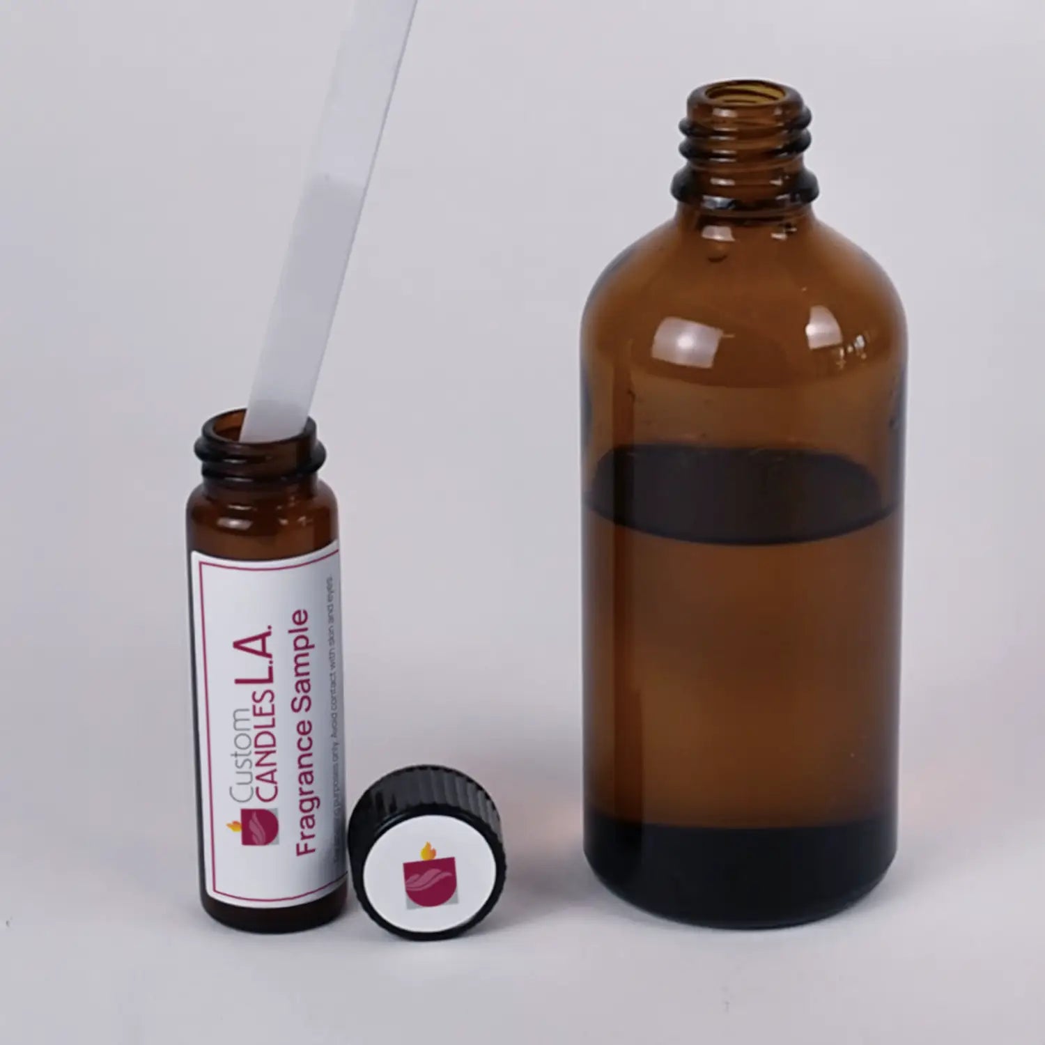 Two amber glass bottles with dropper and cap on a light gray background