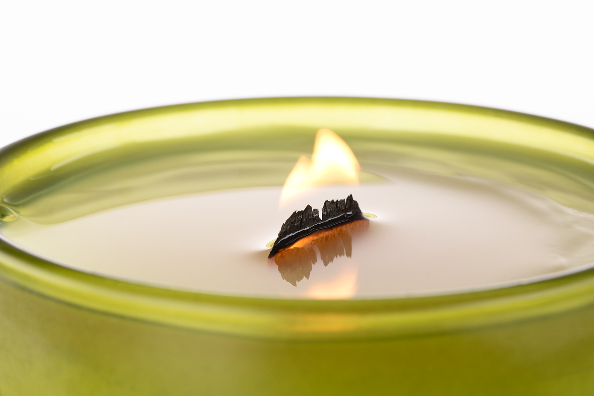 Green 14 oz. Luxury Engraved Candle burning, close-up of the flame and wax pool.