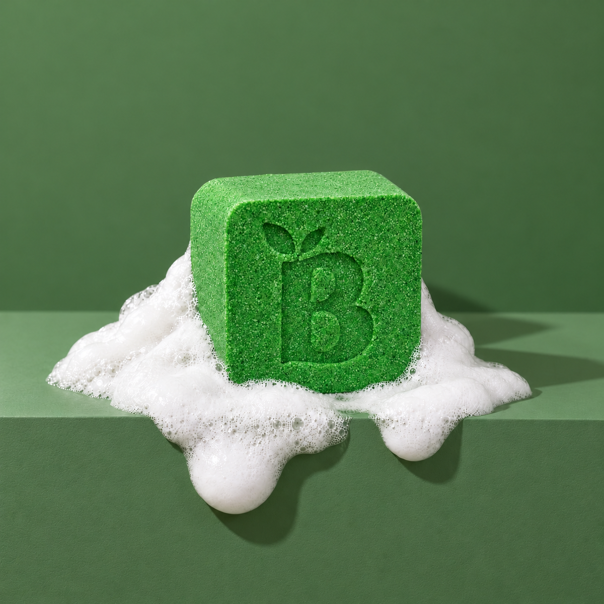 Green custom bath bomb with a debossed brand logo on a green backdrop, resting in white foam