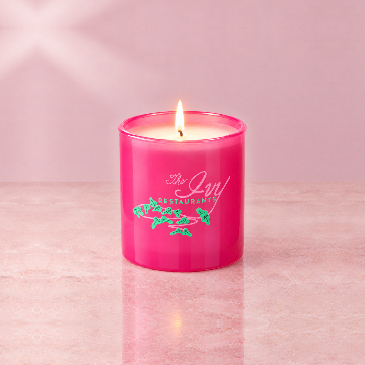 Pink 9 oz. Classic Printed Candle lit with a printed custom logo, shown on a matching pink background.