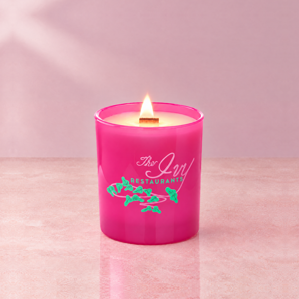 Pink 14 oz. Luxury Printed Candle lit with a printed custom logo, shown on a matching pink background.