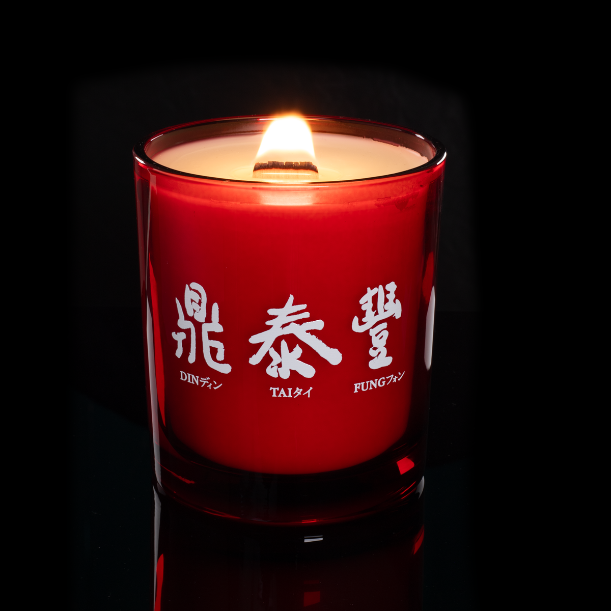 Red 14 oz. Luxury Printed Candle lit, shown on a black background.