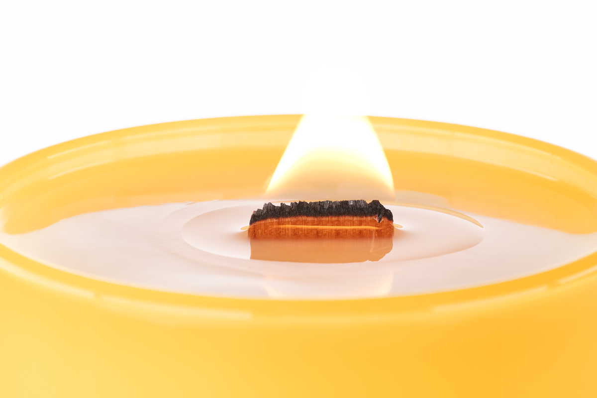 Yellow 14 oz. Luxury Printed Candle burning, close-up of the flame and wax pool.