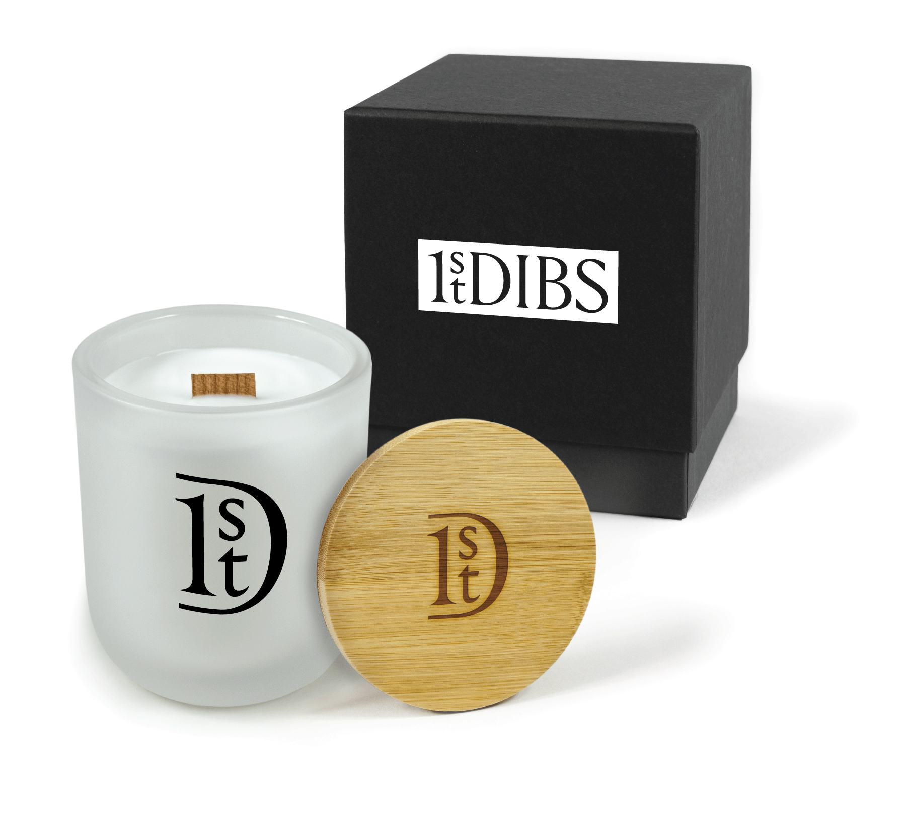 A 12 oz Luxe Custom Candle in the color “Cashmere” which is a diffused white from Custom Candles LA. The candle features a wood wick and black imprinted logo icon for “1st Dibs” on the front of the glass. Leaning against the side of the candle is a bamboo candle lid etched with the logo icon for “1st Dibs”. In the background, there is a black 2-piece box printed with a white and black logo for “1st Dibs”.