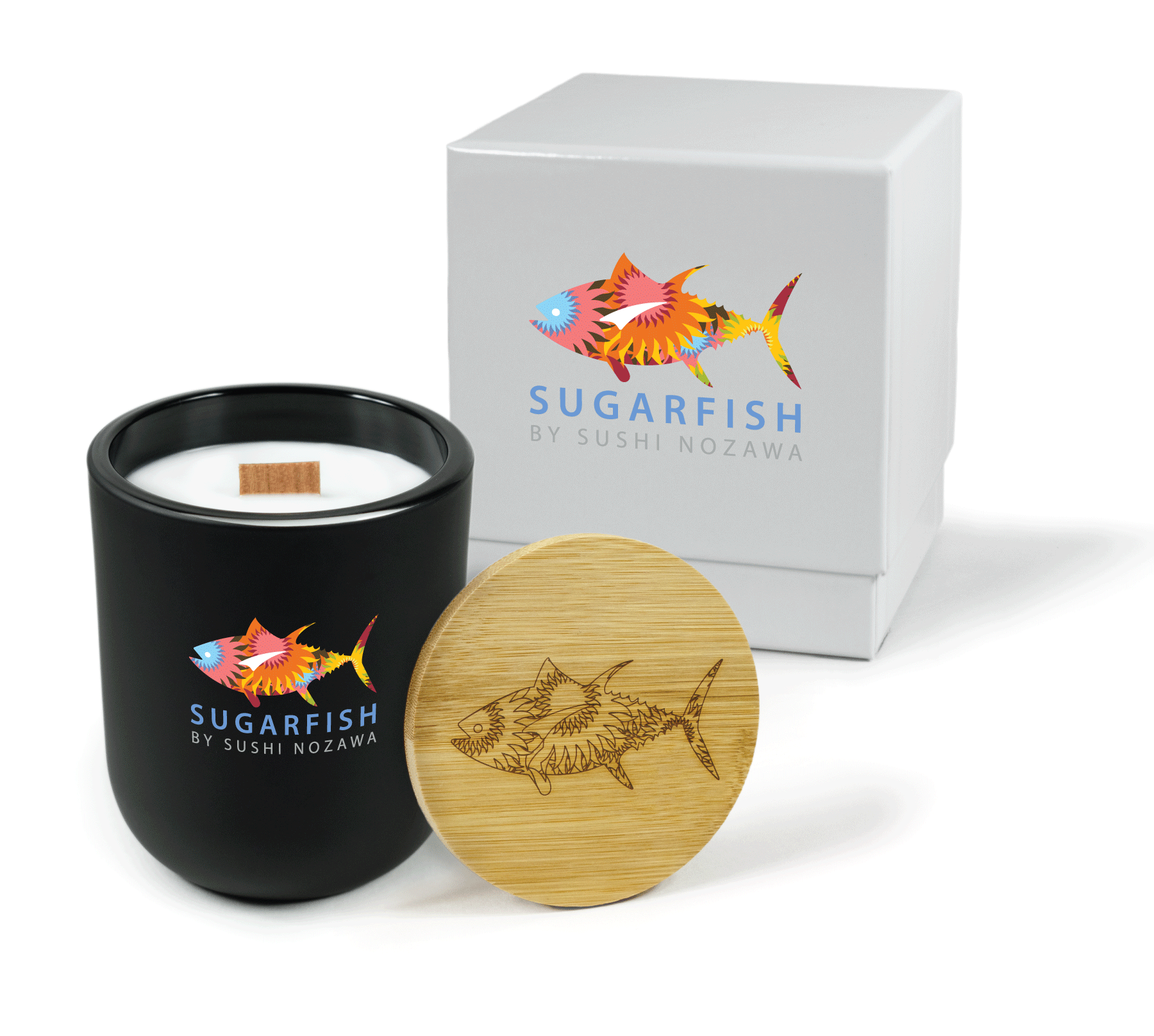 A 12 oz Luxe Custom Candle in the color “Darkest Night” which is a jet black from Custom Candles LA. The candle features a wood wick and a 4-color “Sugarfish by Sushi Nozawa” logo below a multi-colored and patterned fish logo on the front of the glass. Leaning against the side of the candle is a bamboo candle lid etched with the the multi-patterned fish logo. In the background, there is a white 2-piece box 4-color printed with the same “Sugarfish by Sushi Nozawa” and colorful fish logos.