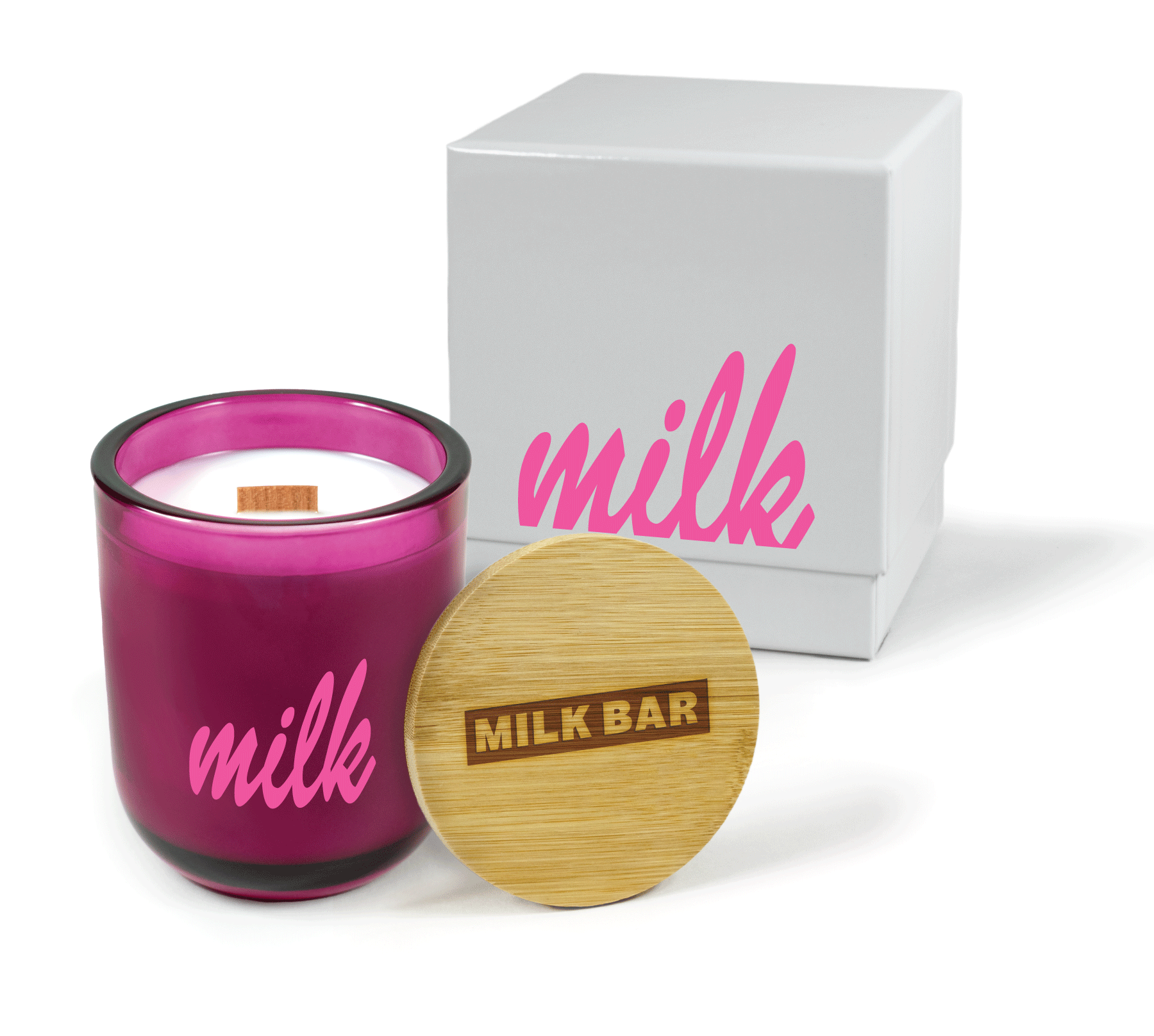 A 12 oz Luxe Custom Candle in the color “Cherry Kiss” which is a juicy magenta from Custom Candles LA. The candle features a wood wick and a 4-color pink imprinted “Milk” logo on the front of the glass. Leaning against the side of the candle is a bamboo candle lid etched with the “Milk Bar” logo. In the background, there is a white 2-piece box 4-color printed with bright pink logo for “Milk”.