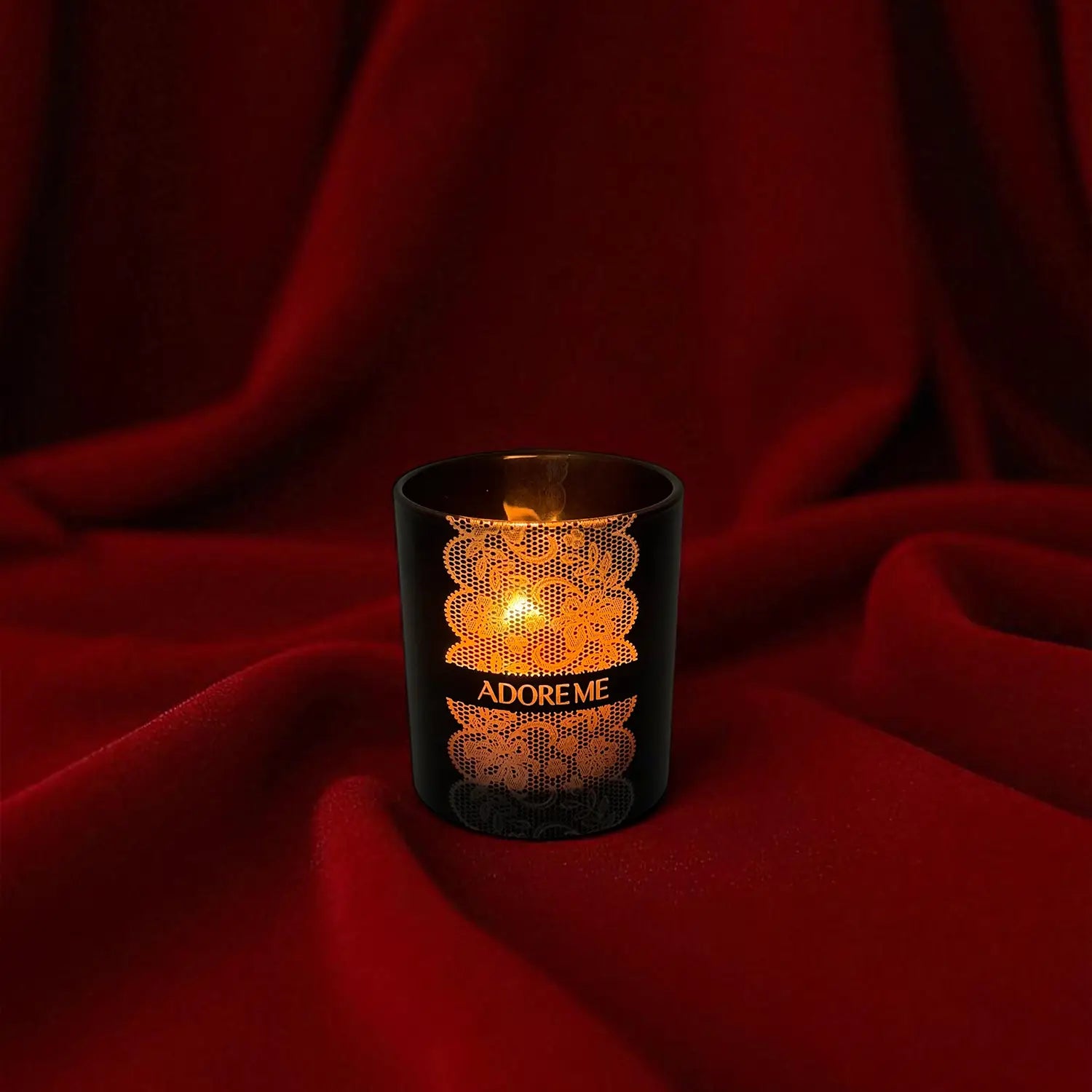Engraved candle in a black holder with intricate design on a red fabric background