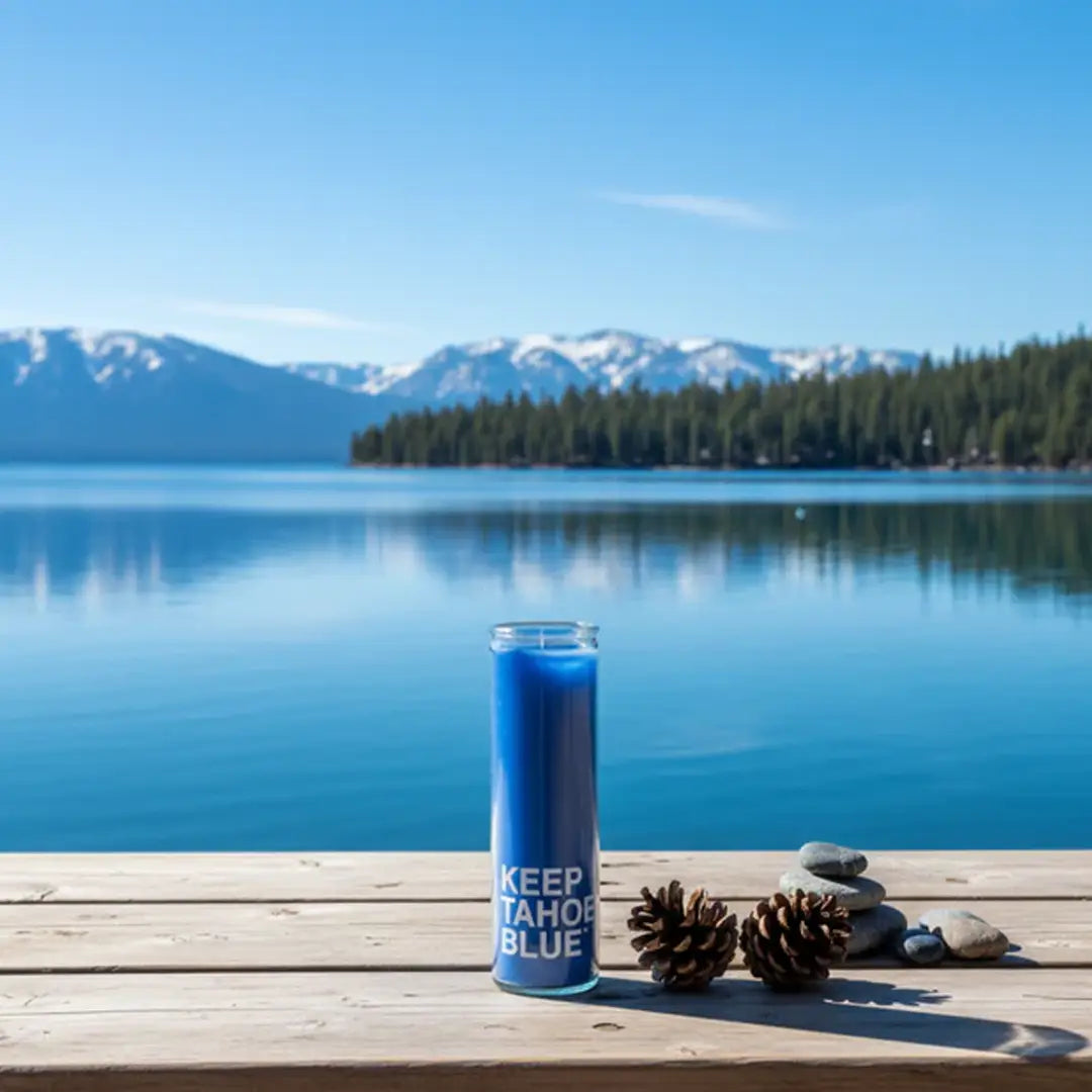 Blue candle with text on a wooden dock with a lake and mountains in the background