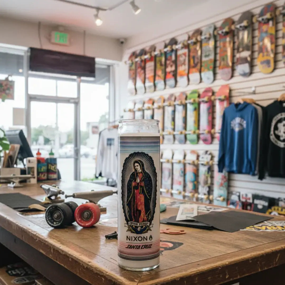 Candle with Virgin Mary design on a counter in a store with skateboards and clothing in the background