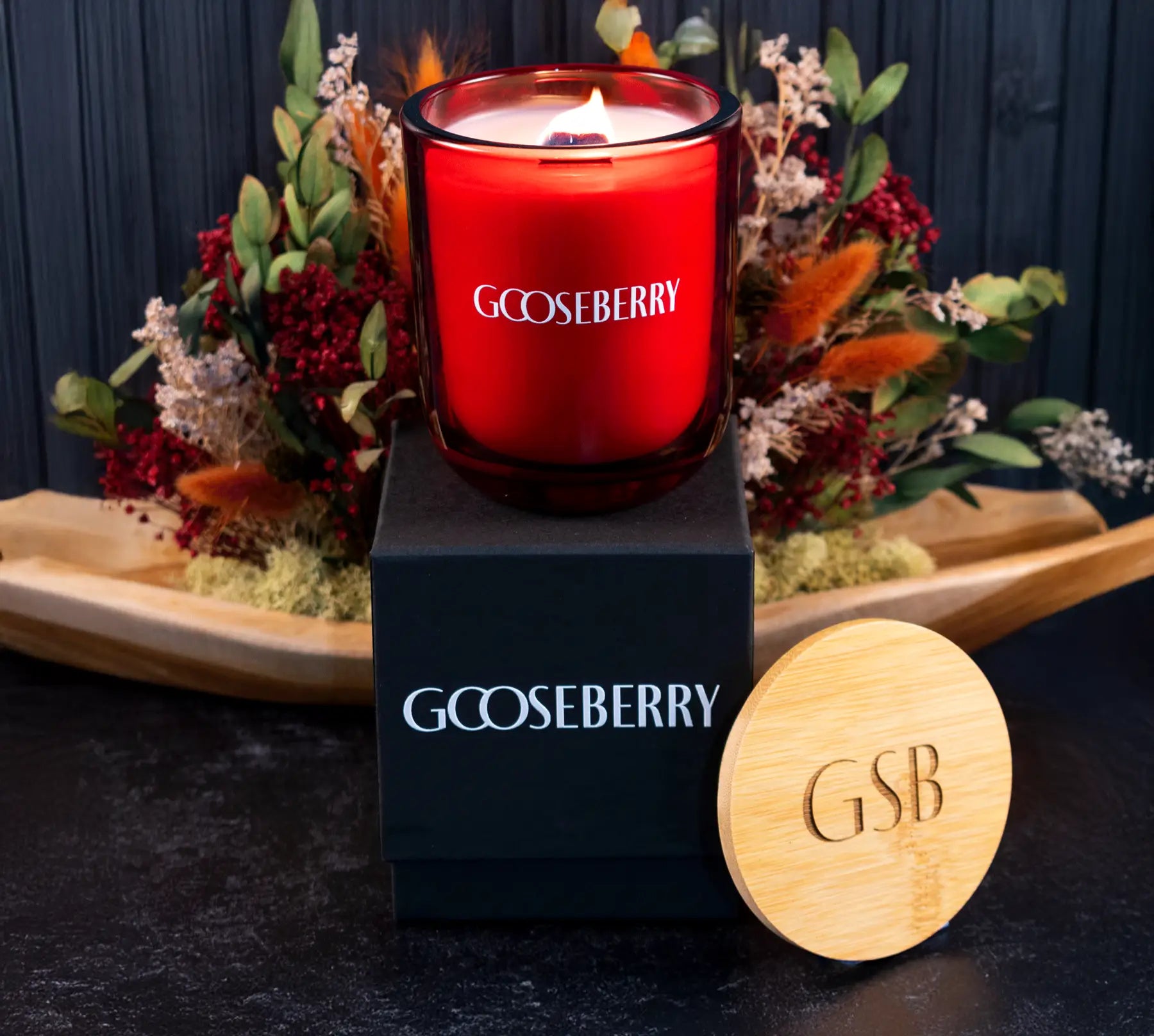 Red candle labeled with a wooden coaster featuring letters on a decorative background.