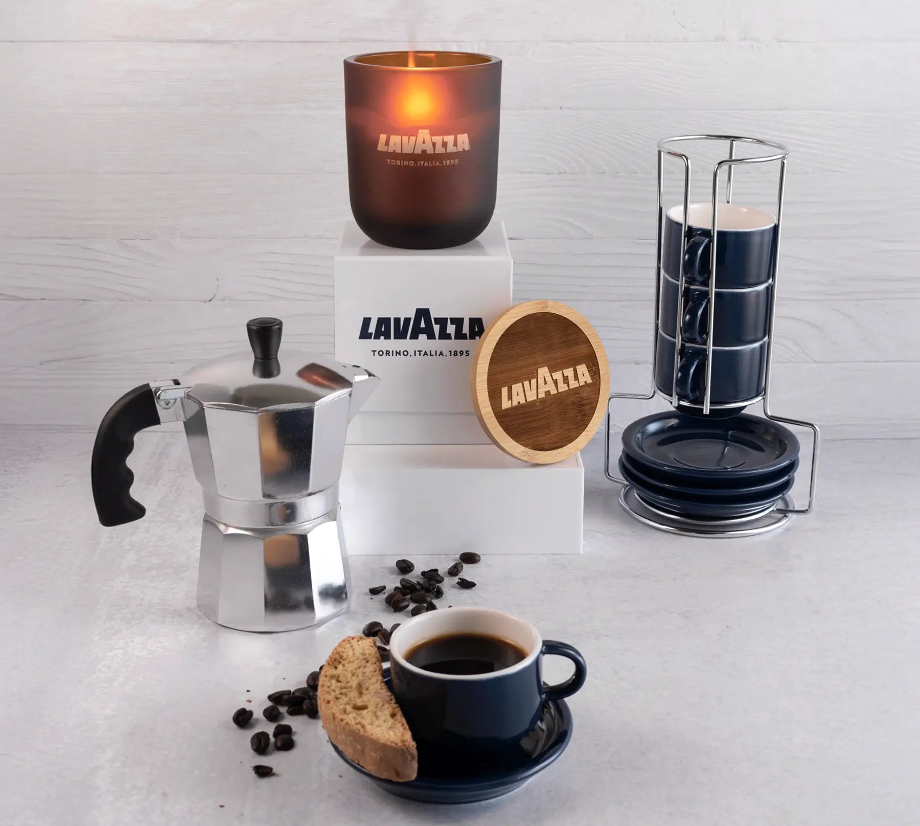 Café setting with coffee-making items and a candle on a light gray background