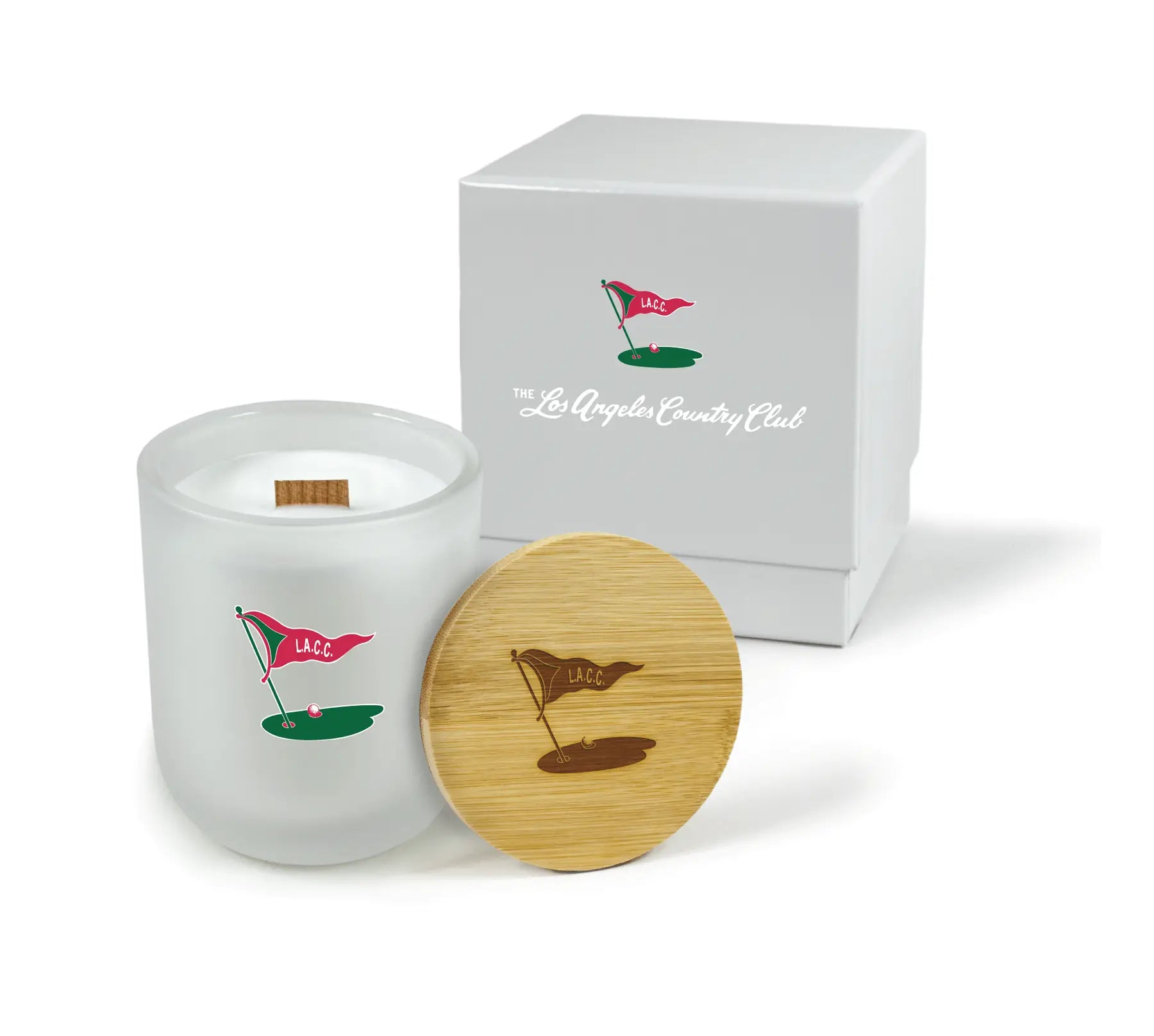White candle with wooden lid featuring golf flag design, next to a white box with logo.