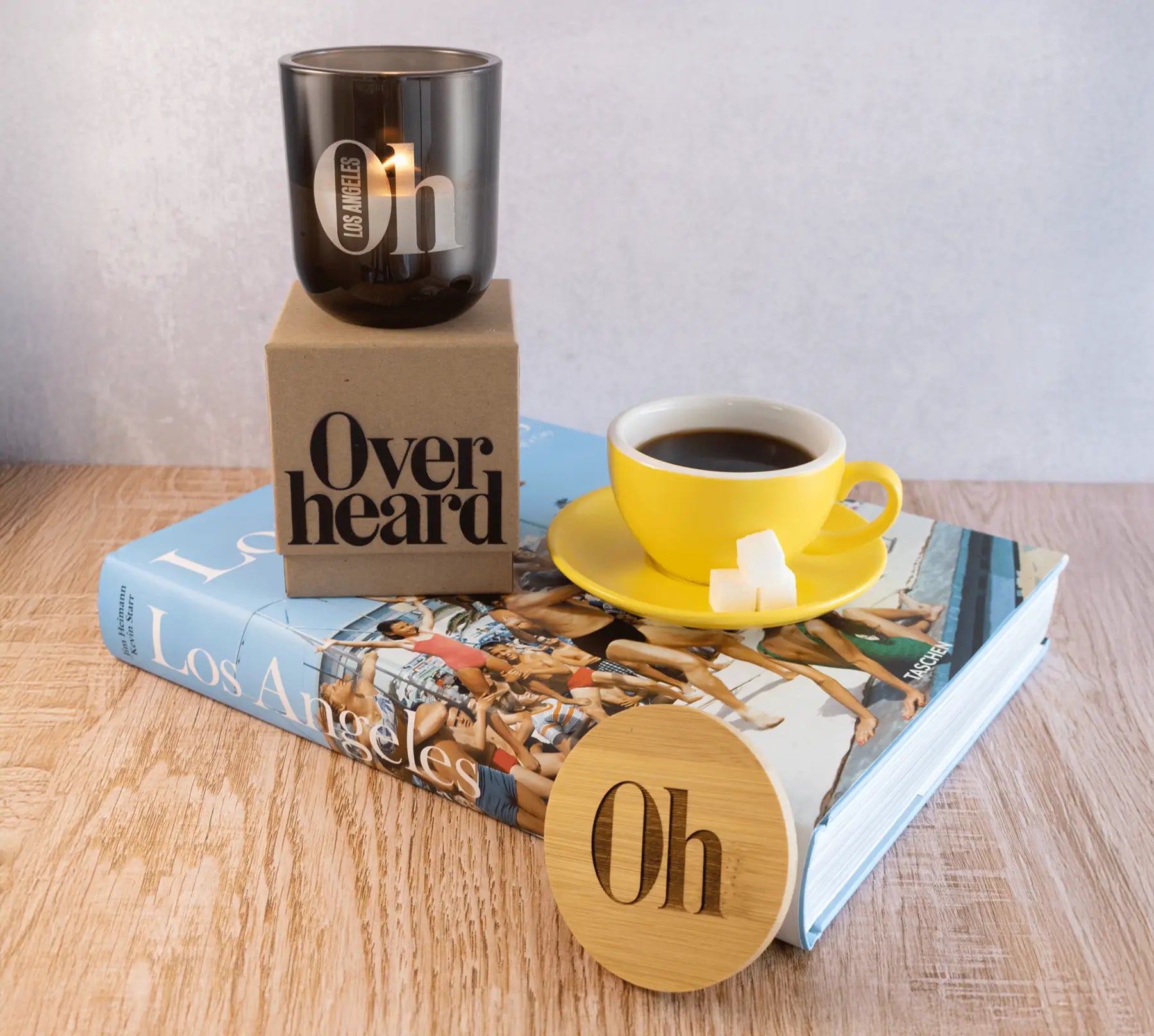 Candle, book, coffee cup, and decorative items on a wooden surface