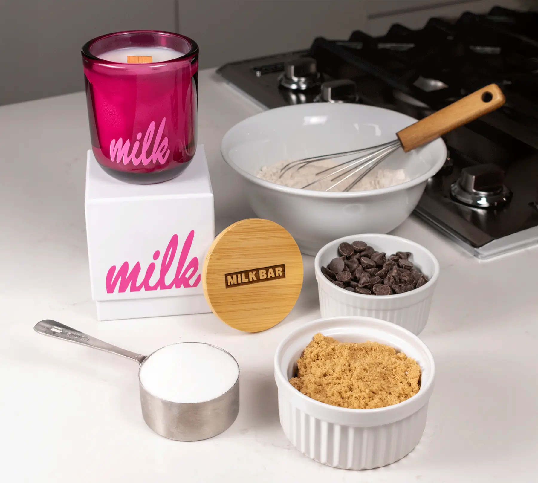 Baking ingredients and utensils on a kitchen counter with pink branding.