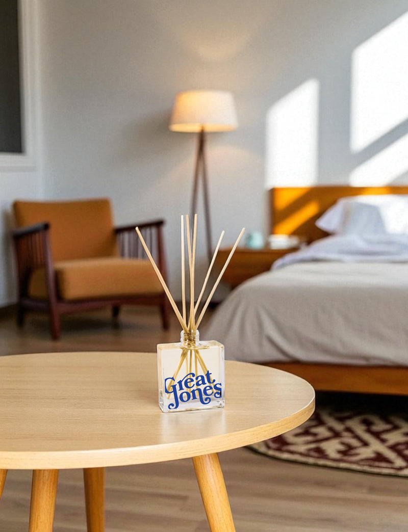 Diffuser with 'Great Jones' branding on a wooden table in a bedroom setting