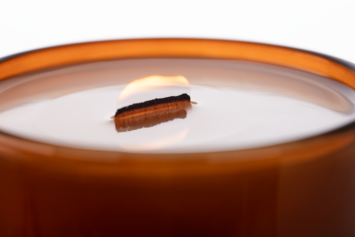 Glossy Amber 14 oz. Luxury Engraved Candle burning, close-up of the flame and wax pool.