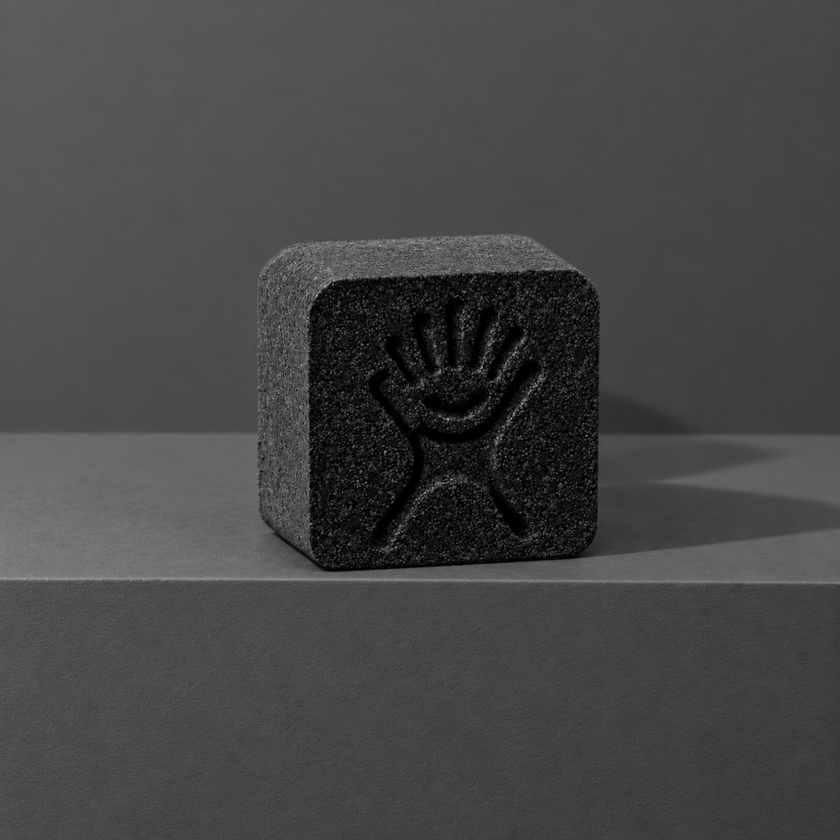 Black custom bath bomb with a debossed brand logo on a dark gray backdrop, no foam