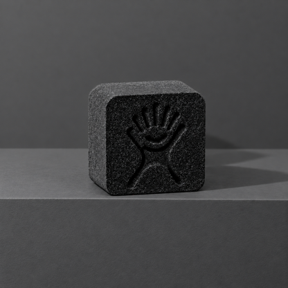 Black custom bath bomb with a debossed brand logo on a dark gray backdrop, no foam