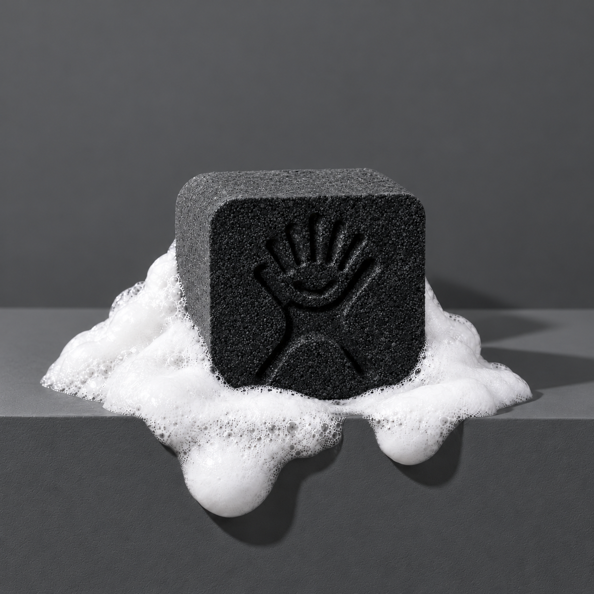 Black custom bath bomb with a debossed brand logo on a dark gray backdrop, resting in white foam