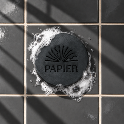 Black round bar soap laser engraved with a brand logo, 3.6 oz, with soap bubbles
