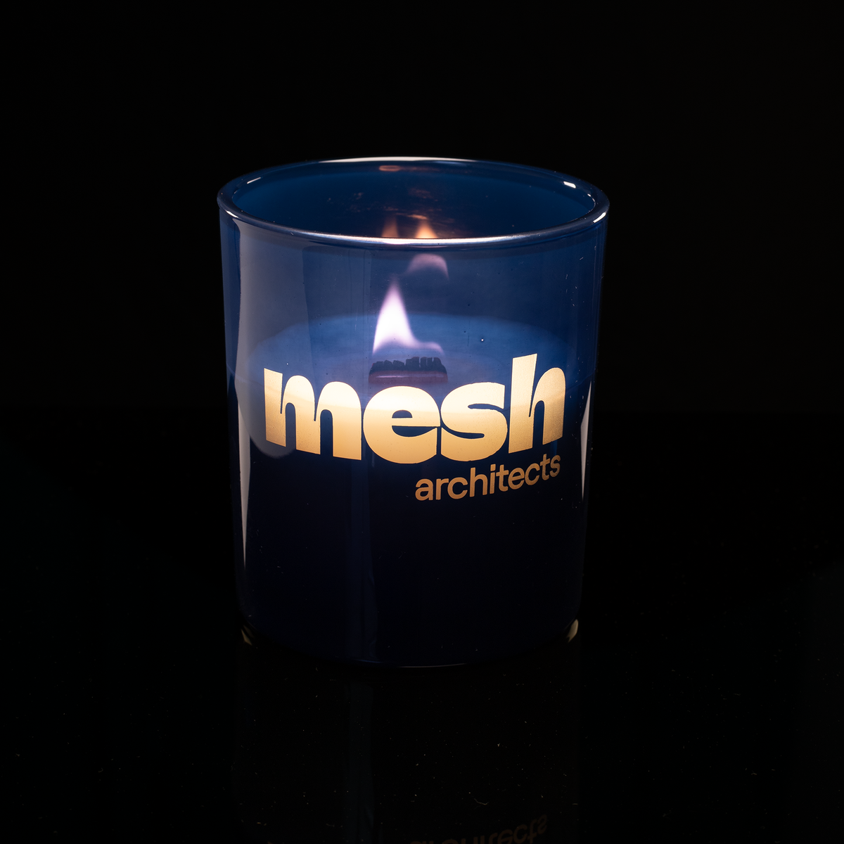 Blue 14 oz. Luxury Engraved Candle lit, shown on a black background.