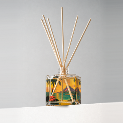 Clear glass 8 oz. reed diffuser with natural reeds and a colorful printed design, on a white ledge against a soft gray backdrop