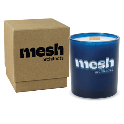 Blue colored-glass 14 oz candle beside a kraft gift box.