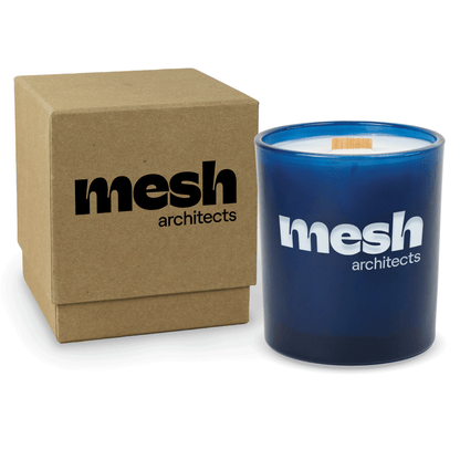 Blue 14 oz colored glass engraved logo candle beside a kraft gift box on a white background.