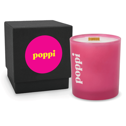 Pink 14 oz colored glass engraved logo candle beside a matte black gift box on a white background.