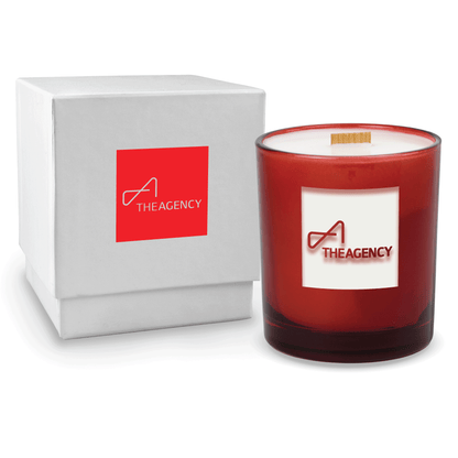 Red colored-glass 14 oz candle beside a glossy white gift box.