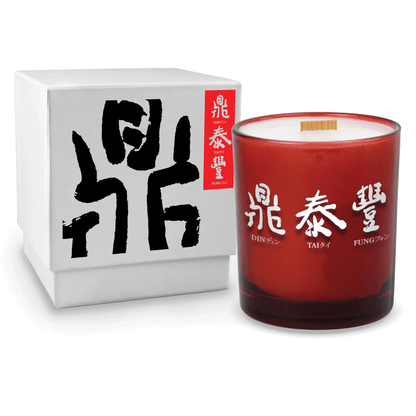 Red colored-glass 14 oz candle beside a glossy white gift box.
