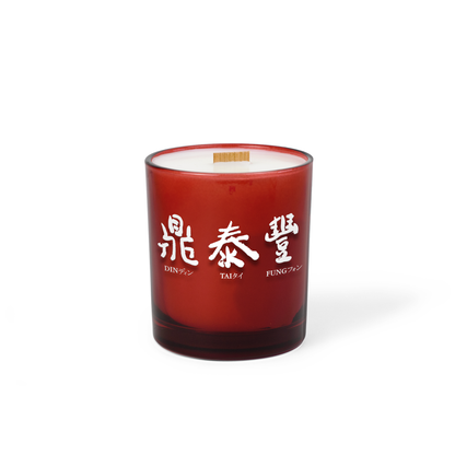 Red colored-glass 14 oz candle with a printed brand logo, shown on its own.
