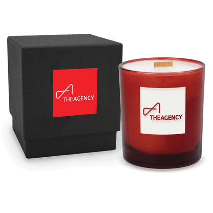 Red 14 oz colored glass engraved logo candle beside a matte black gift box on a white background.