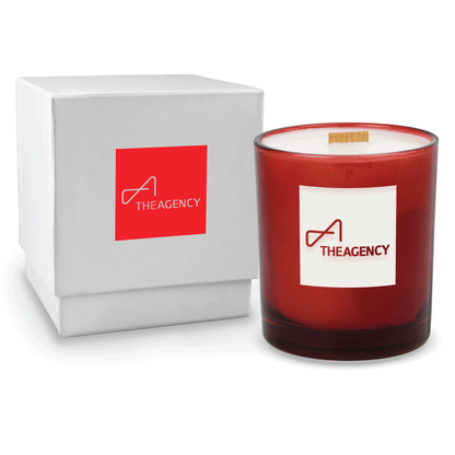 Red 14 oz colored glass engraved logo candle beside a glossy white gift box on a white background.
