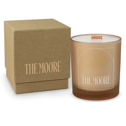 Sand 14 oz colored glass engraved logo candle beside a kraft gift box on a white background.