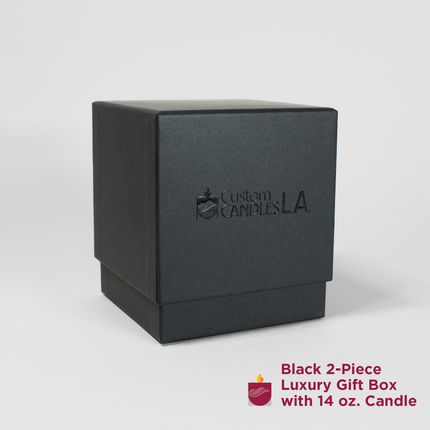 A black,, square, two-piece luxury gift box is centered on a plain background. The box features "Custom Candles LA" in subtle embossed text on the front of the box.. An icon of a candle with flame and the text "Black 2-Piece Luxury Gift Box with 14 oz. Candle" are at the bottom right.