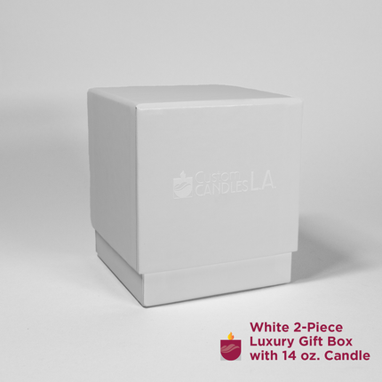 A white, square, two-piece luxury gift box is centered on a plain background. The box features "Custom Candles LA" in subtle embossed text on the front of the box. An icon of a candle with flame and the text "White 2-Piece Luxury Gift Box with 14 oz. Candle" are at the bottom right.