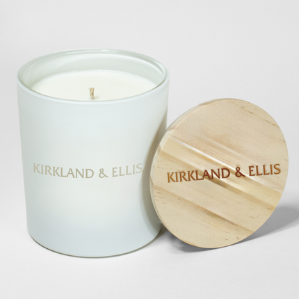 A 14 oz deluxe "Design Your Own" white tumbler candle from Custom Candles LA. The candle features an etched logo reading "Kirkland & Ellis"on the vessel and the logo "Kirkland & Ellis" engraved on a wooden lid.