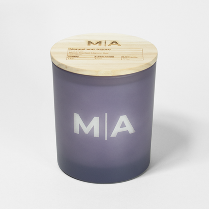 The "Monogram For The Record" candle is featured in a frosted lavendar candle from Custom Candles LA, with the monogram "M|A" etched into the glass with white wax showing through. The lid is engraved with the monogram "M|A" following by a box filled with details about a first date.