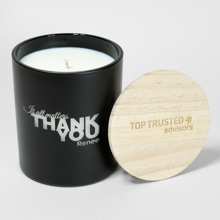 The "It All Matters Thank You Premium" candle is in a black vessel from Custom Candles LA, featuring white wax and a white wick. The candle is etched with the text "It all matters Thank You Renee"; it comes next to a wooden lid engraved with a logo that reads "Top Trusted advisors".