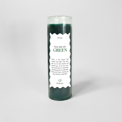 A tall cylindrical candle in a glass container filled with green wax titled "You are my GREEN" on a white label with scalloped edges. The label also includes a note explaining what the color green represents followed by a green heart at the bottom.