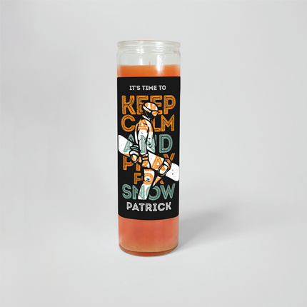 A 16 oz Prayer candle from Custom Candles LA featuring an orange candle with art of a snowboarder and the words "It's Time To keep calm and pray for snow Patrick" printed on a black label..