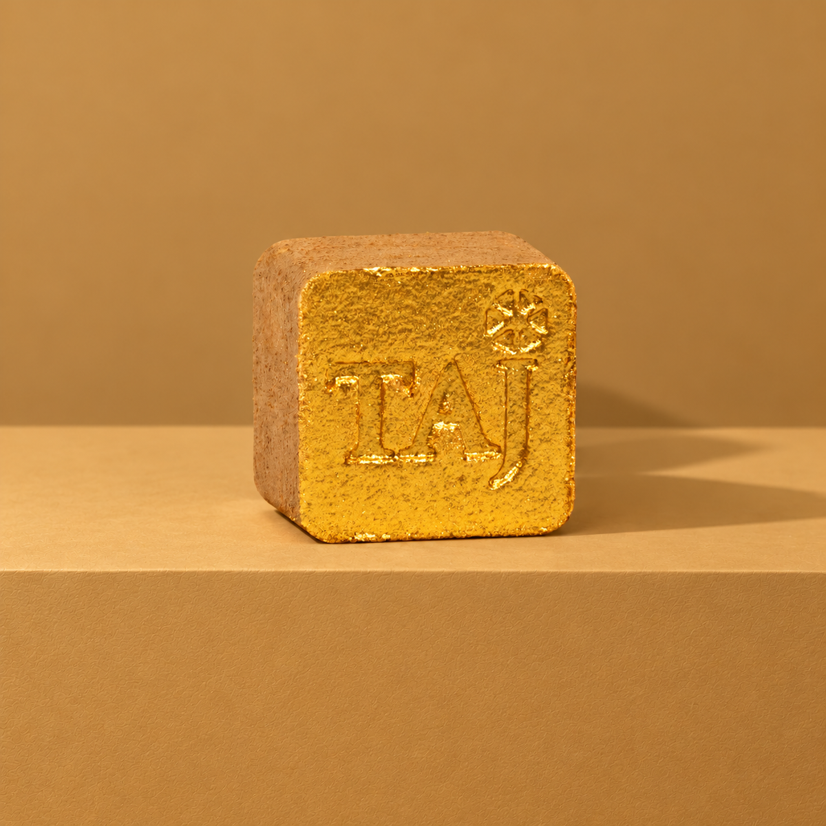 Gold custom bath bomb with a debossed brand logo on a golden backdrop, no foam