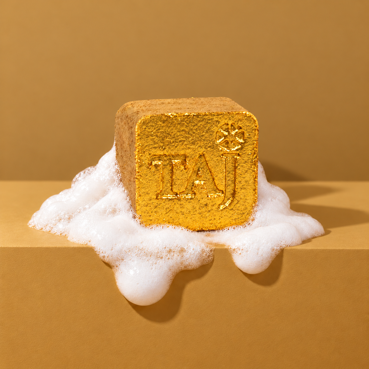 Gold custom bath bomb with a debossed brand logo on a golden backdrop, resting in white foam