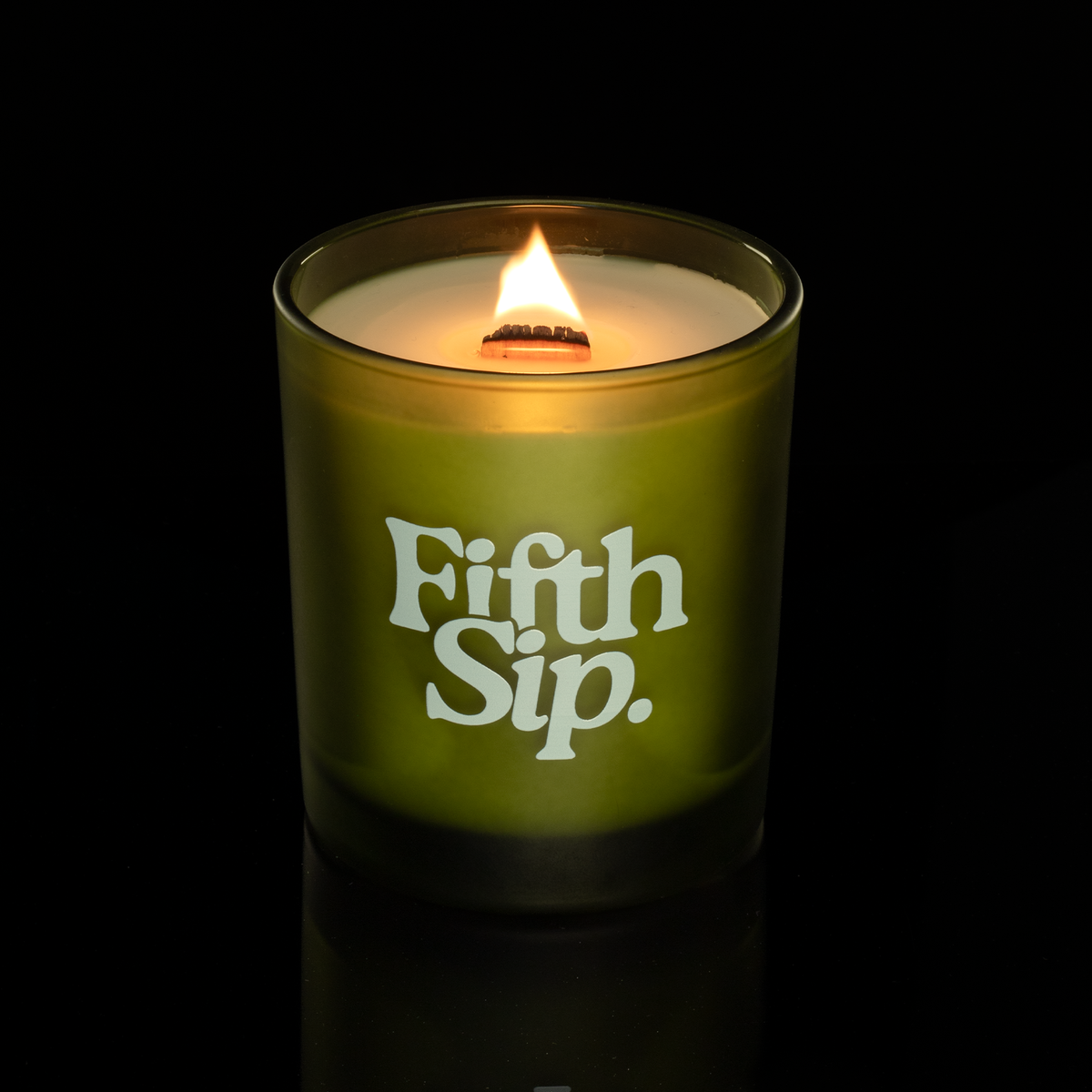 Green 14 oz. Luxury Printed Candle lit, shown on a black background.