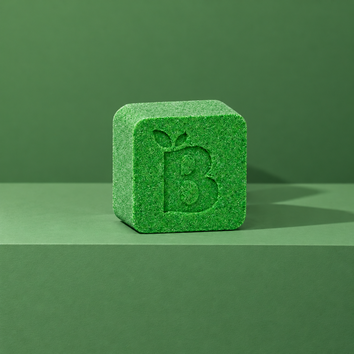 Green custom bath bomb with a debossed brand logo on a green backdrop, no foam