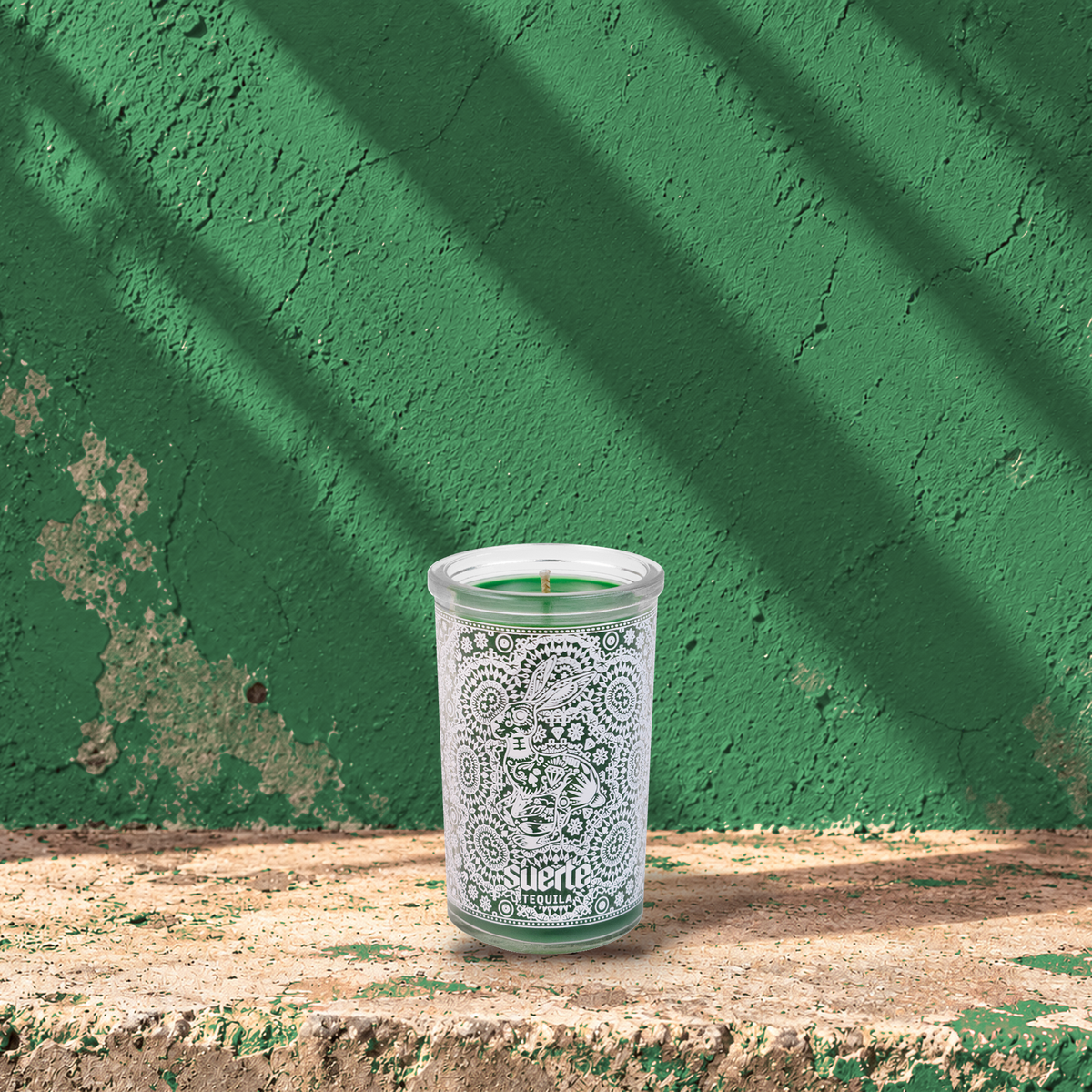 Green 5 oz custom mini prayer candle printed with the Suerte Tequila logo on a green background, unlit
